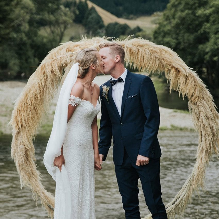 Feature-Jess-Daisy-Aster-wedding-dress-couple-kissing-wreath