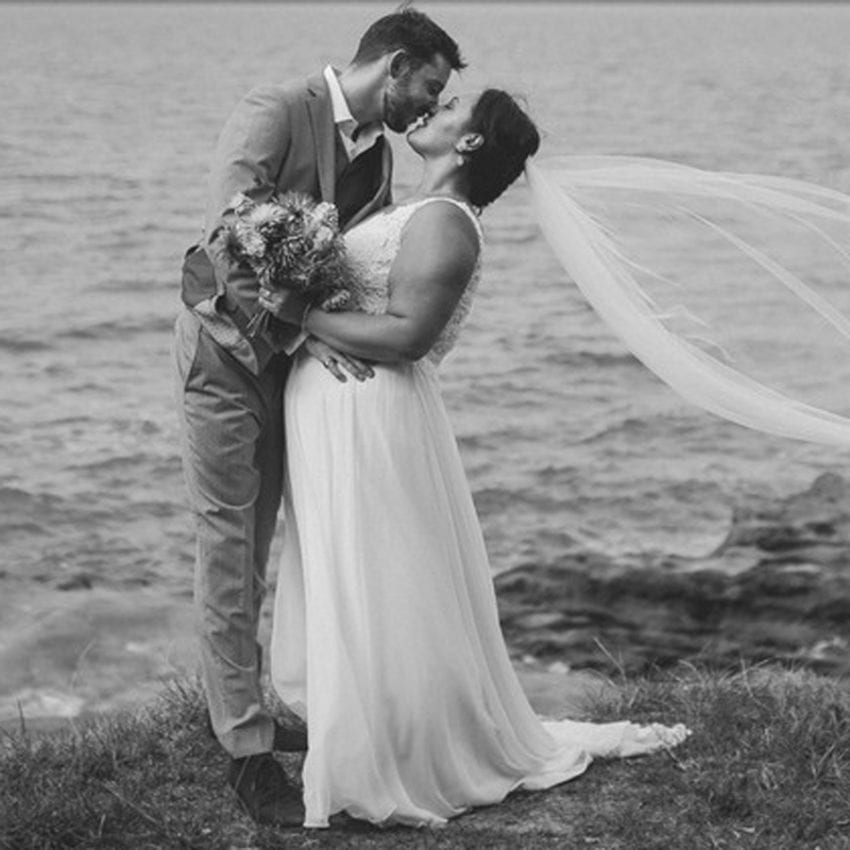 Feature-Jenny-chris-daisy-snow-lotus-wedding-dress-bride-groom-kissing-veil-water-black-and-white