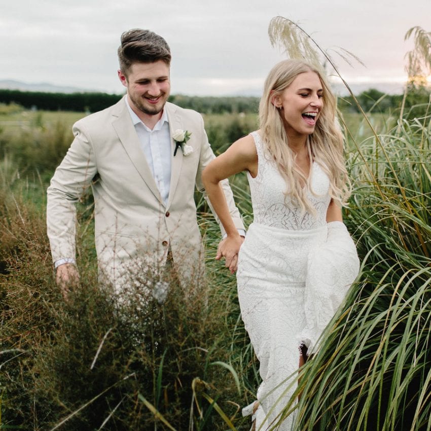 Paige&Charlie-wedding-dress-desert-lily-sunset-holding-hands-field-854-feature
